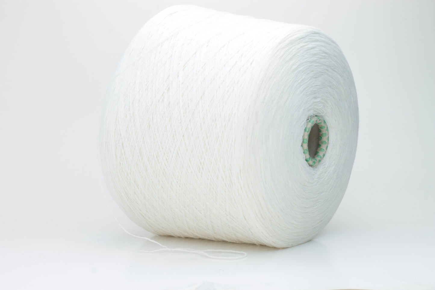Close-up of a pristine white, two-ply cashmere yarn ball, subtly glowing with a luxurious, fine-fibered halo.
