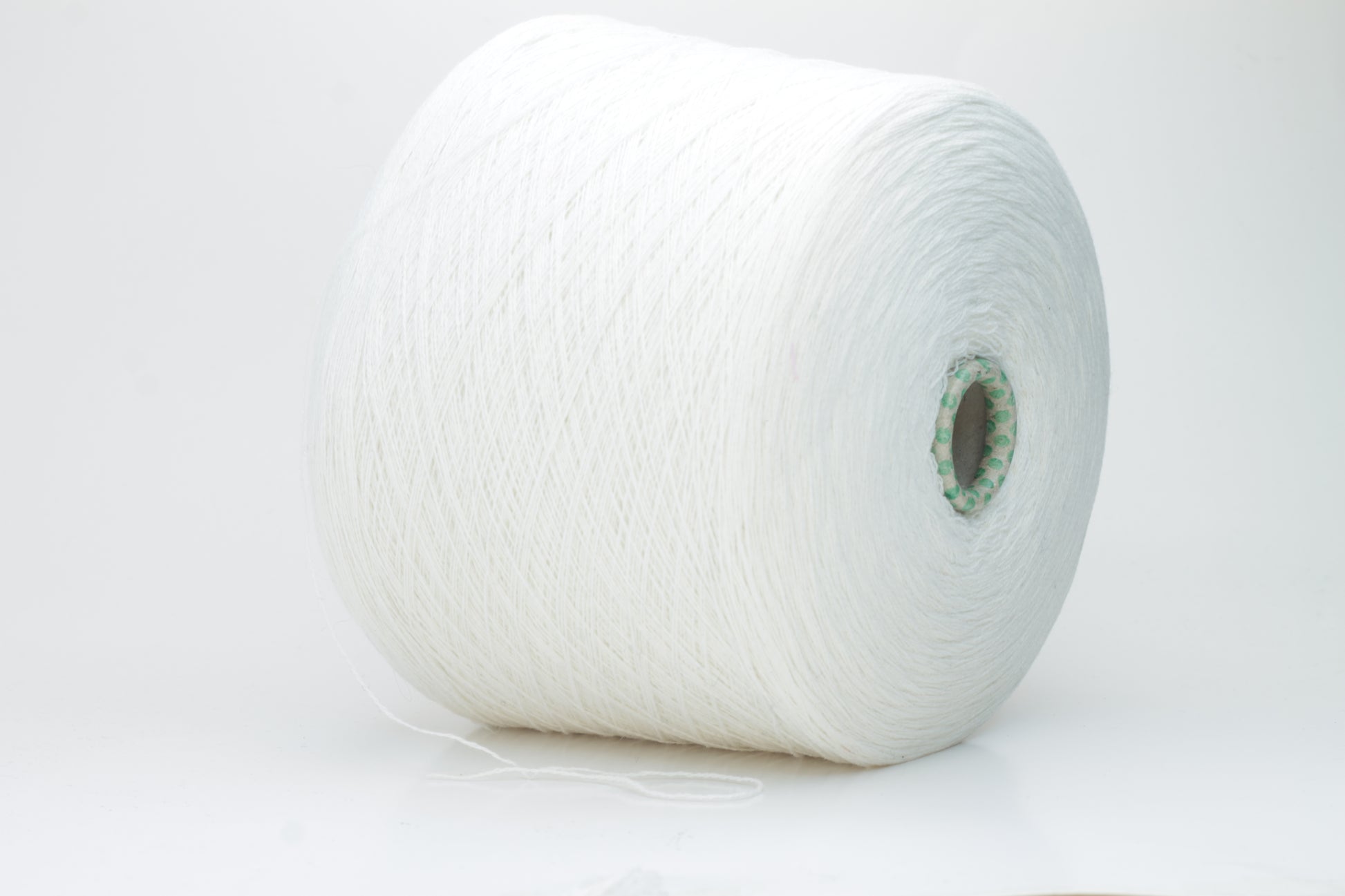 Close-up of a pristine white, two-ply cashmere yarn ball, subtly glowing with a luxurious, fine-fibered halo.