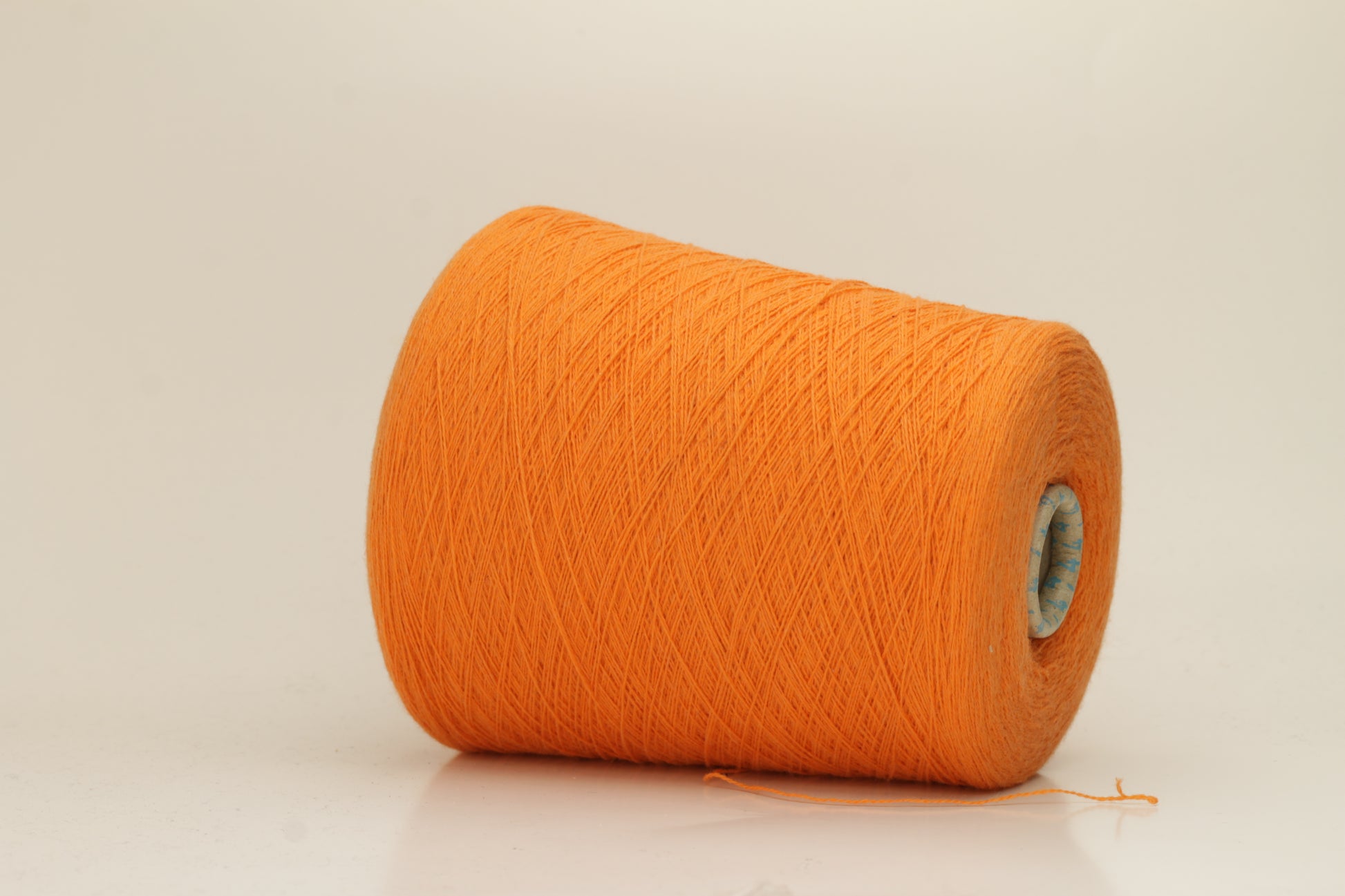 Close-up of fluffy, deeply saturated Jaffa orange cashmere yarn, showing its soft, slightly twisted two-ply structure and delicate sheen.