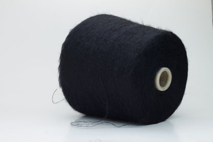 Close-up shot of the Black SuperKidMohair yarn, showcasing its dense ply twist and subtle sheen. The fibers appear fluffy and richly colored, creating a luxurious tactile impression.