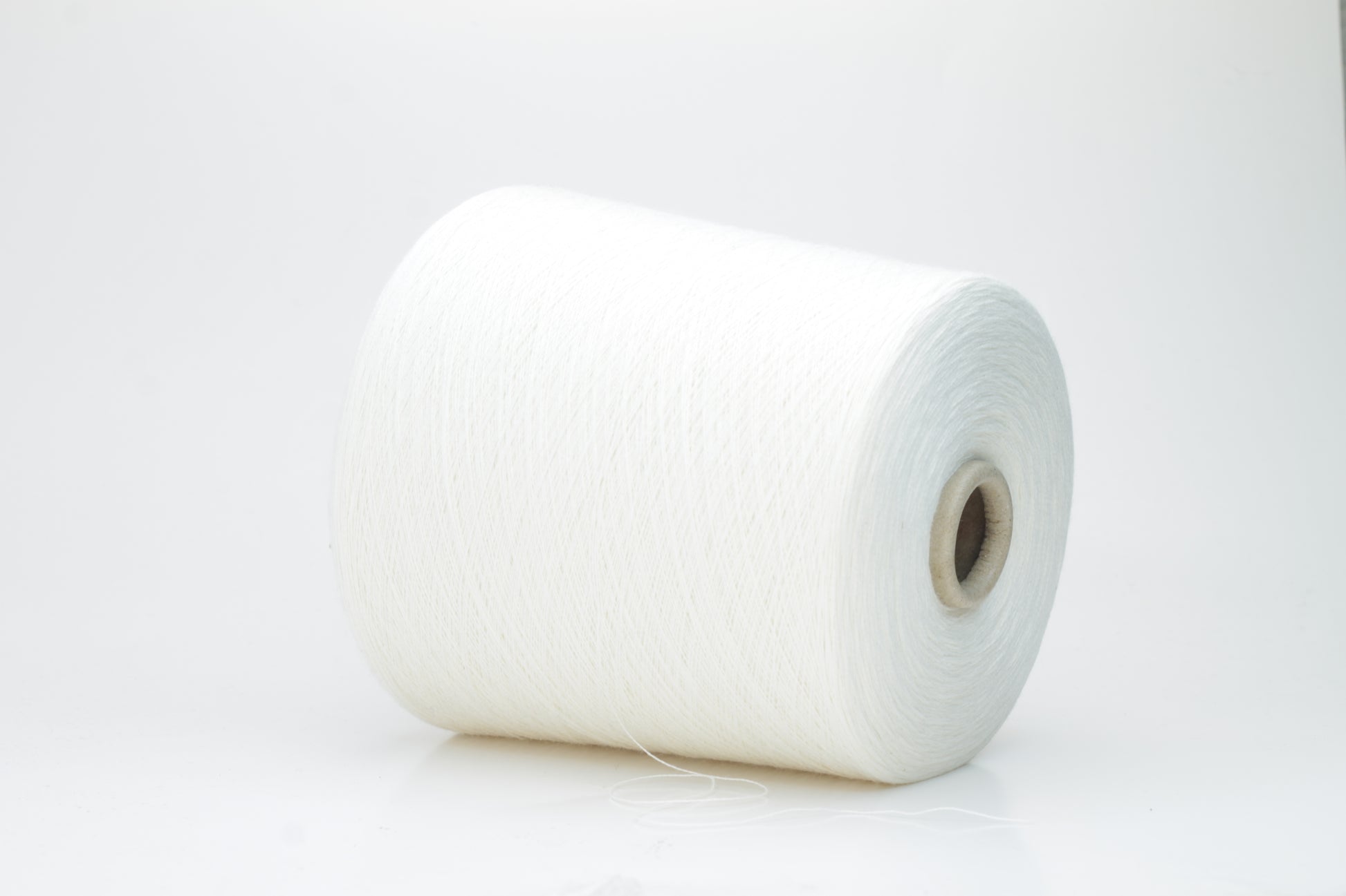 Close-up view of a creamy white, fluffy yarn strand with subtle sheen. The yarn shows a twisted ply construction and a dense, luxurious texture, hinting at its high cotton and cashmere fiber content.