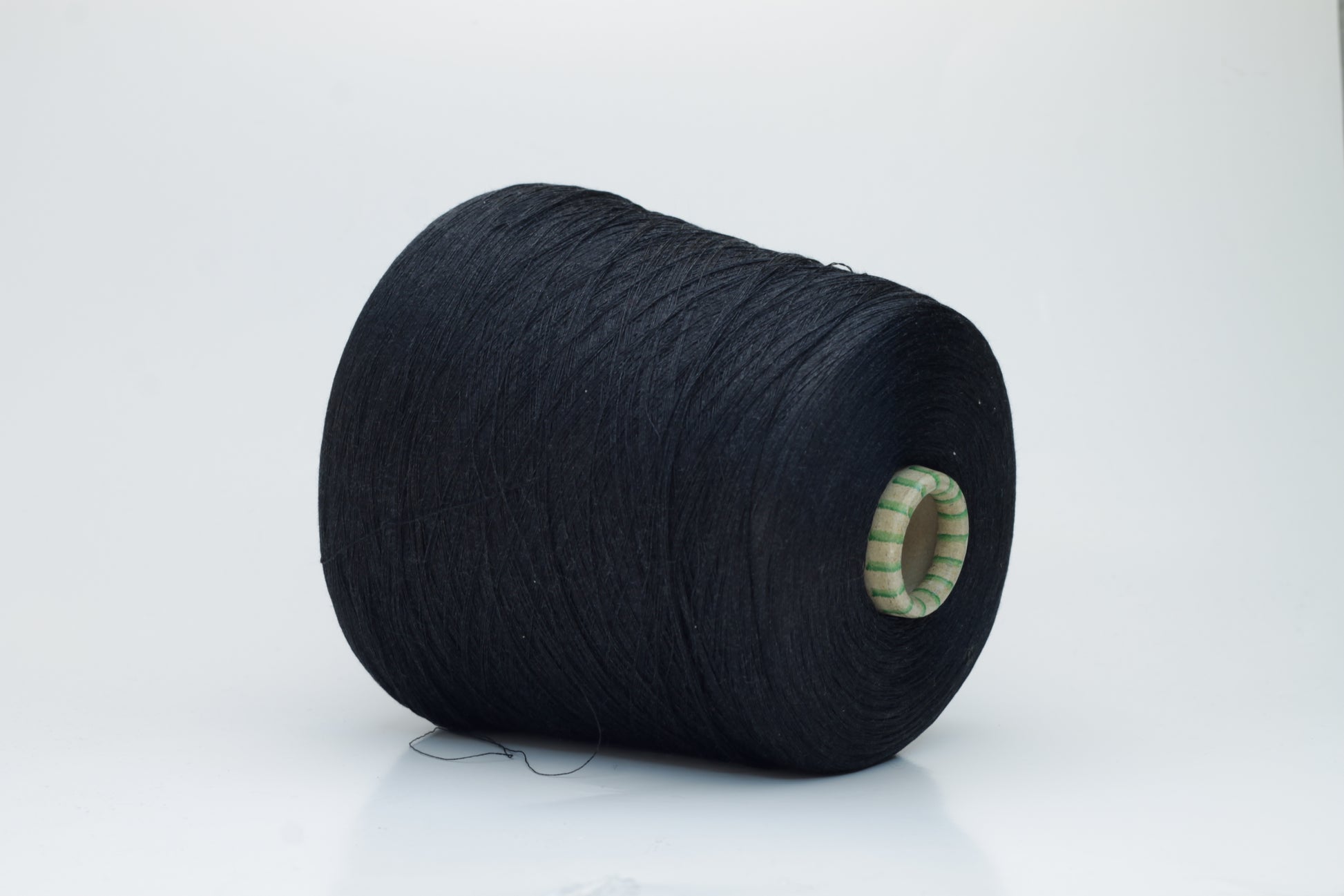 Spool of rich, deep black silk yarn, showcasing its fine, smooth plies and radiant, natural luster against a soft background.