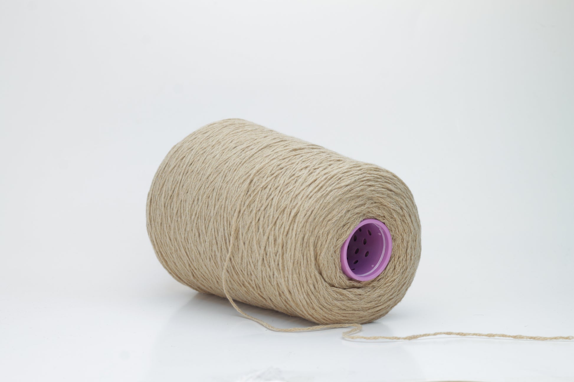 A luxuriously soft skein of pale, warm camel-colored cashmere yarn, gently twisted with a subtle halo, showcasing its delicate and fine fibers.