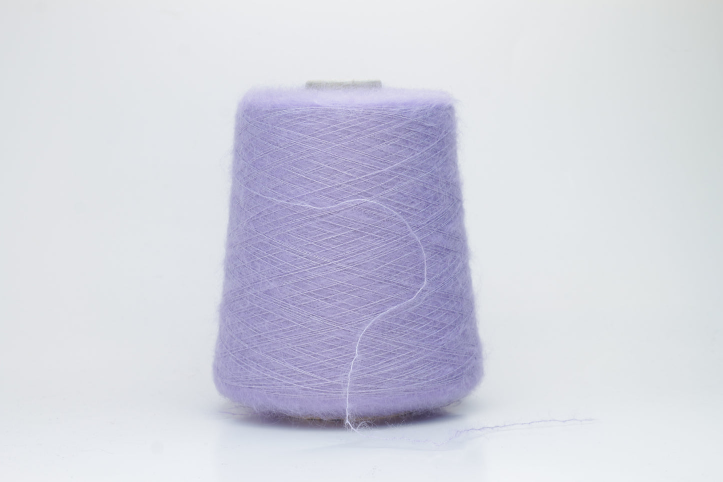 Close-up of fluffy Lila kid mohair and silk blend yarn, subtly lustrous with a soft halo, gently twisted into a fine, delicate thread.