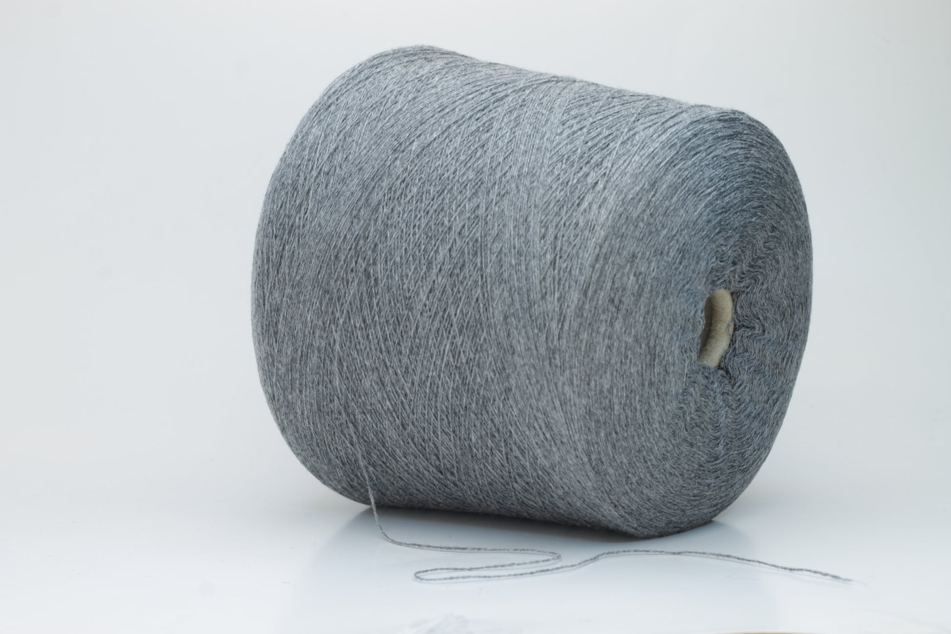 Skein of fine, two-ply cashmere yarn in a sophisticated medium gray, exhibiting a soft, subtle halo and delicate matte sheen.