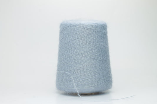Close-up of fluffy Cielo kid mohair and silk blend yarn, subtly lustrous with a soft halo, gently twisted into a fine, delicate thread.