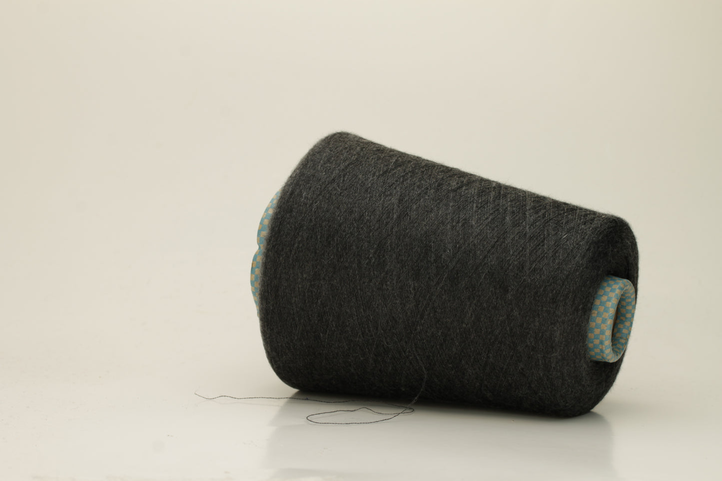 Close-up of a luxurious, finely spun two-ply cashmere silk blend yarn in a soft, elegant gray shade with a subtle sheen, showcasing its delicate texture.