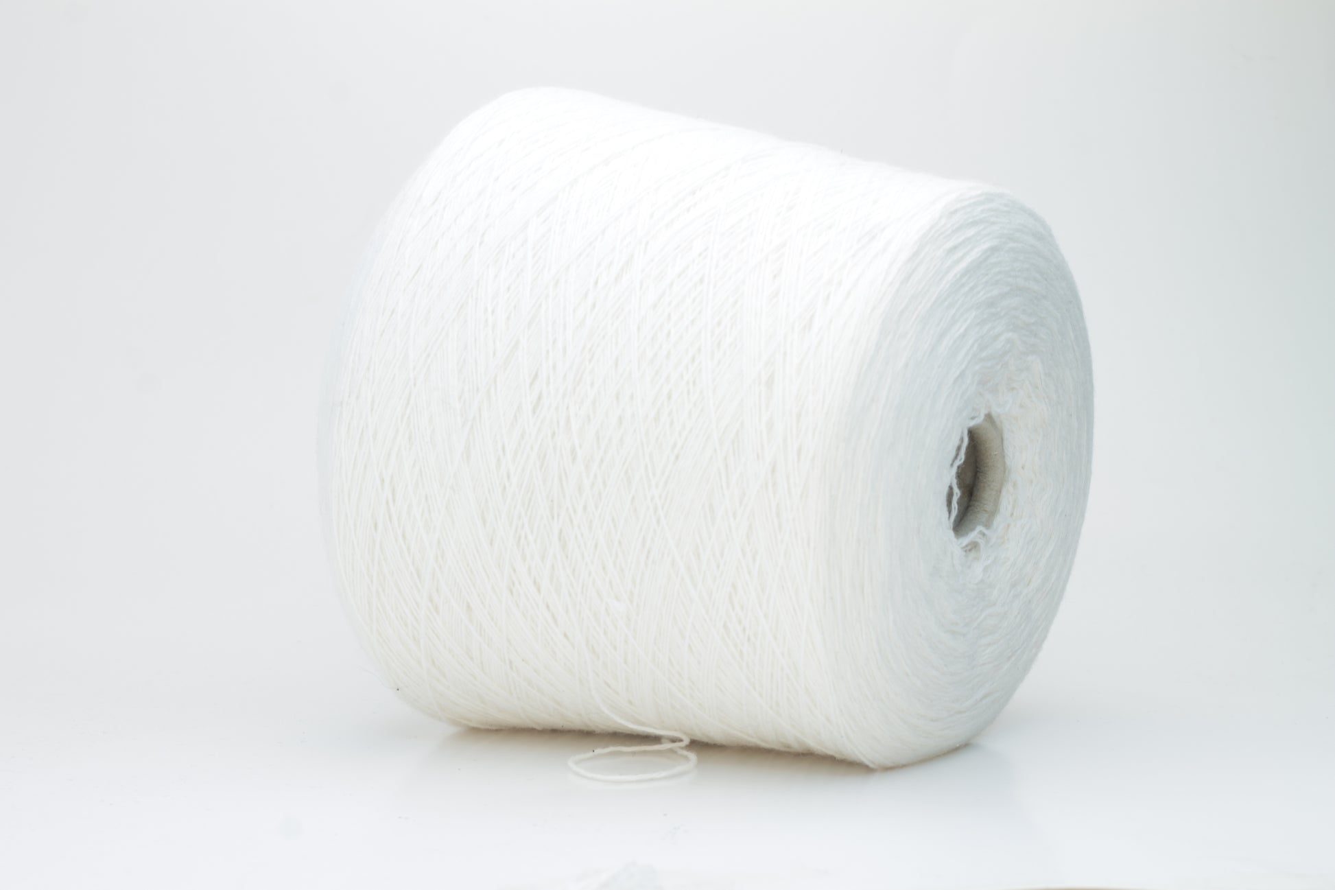 Close-up of a pure white cashmere yarn skein, showcasing its soft, slightly fluffy texture and subtle sheen with a gently twisted, fine two-ply structure.