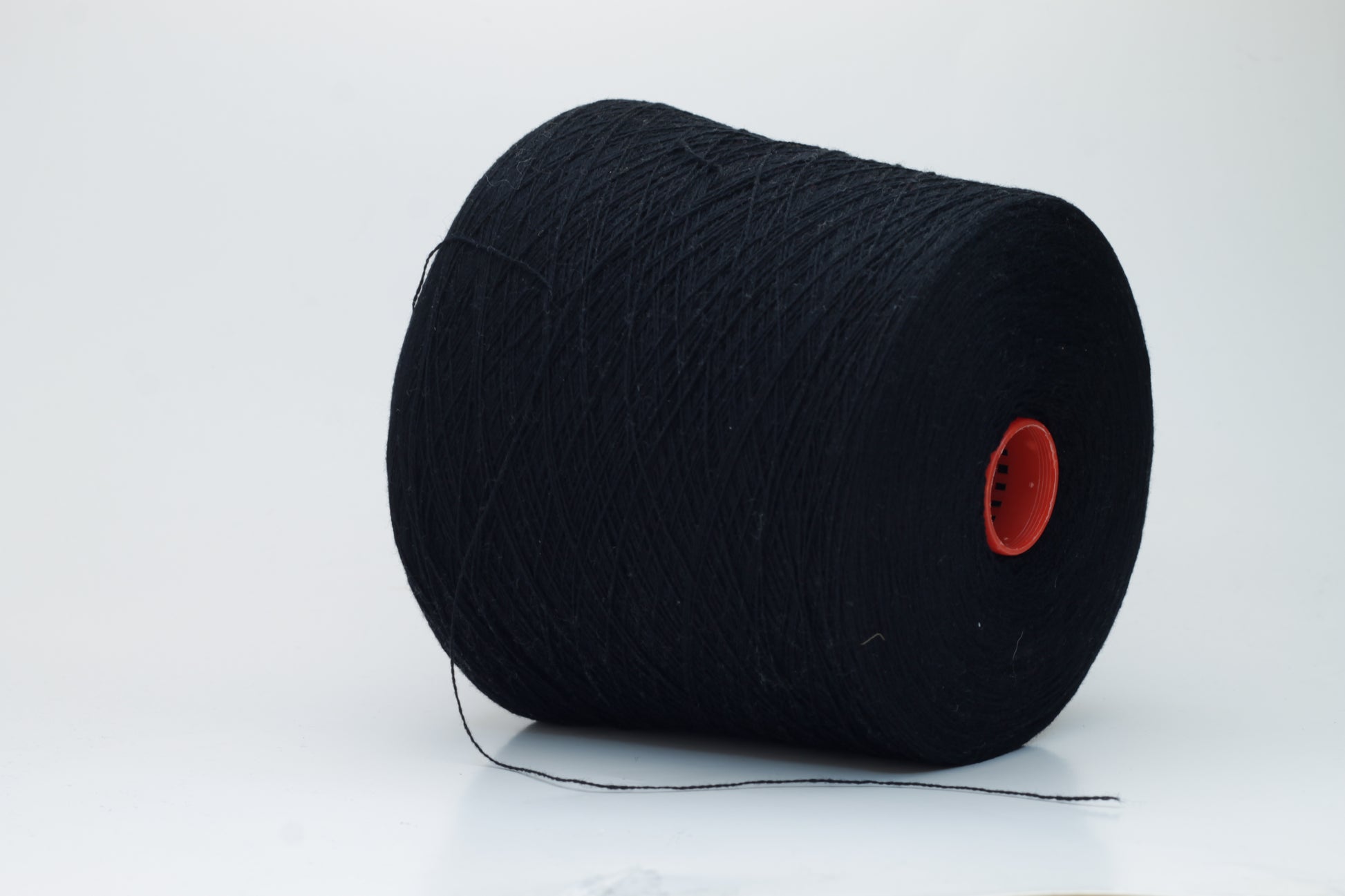 Close-up of a deep black, two-ply cashmere yarn, exhibiting a soft, even twist and a subtle, rich sheen under natural light, indicating its luxurious texture.