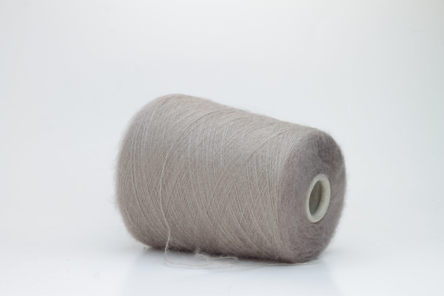 Close-up of fluffy Beige kid mohair and silk blend yarn, subtly lustrous with a soft halo, gently twisted into a fine, delicate thread.