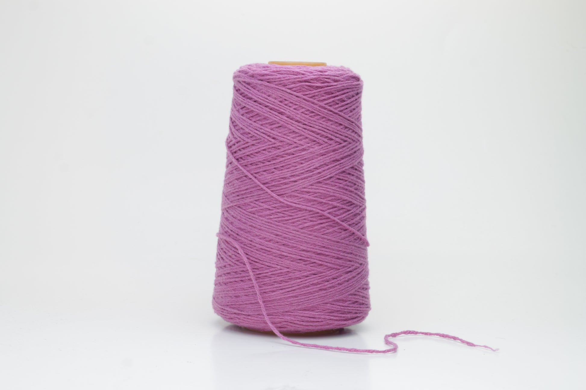 A beautifully wound cone of fine, single-ply cashmere yarn in a soft wisteria purple hue, displaying a delicate halo of fluff and subtle sheen.
