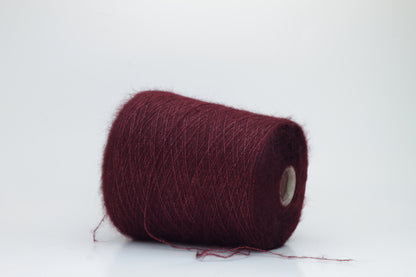 Close-up of fluffy Bordo kid mohair and silk blend yarn, subtly lustrous with a soft halo, gently twisted into a fine, delicate thread.