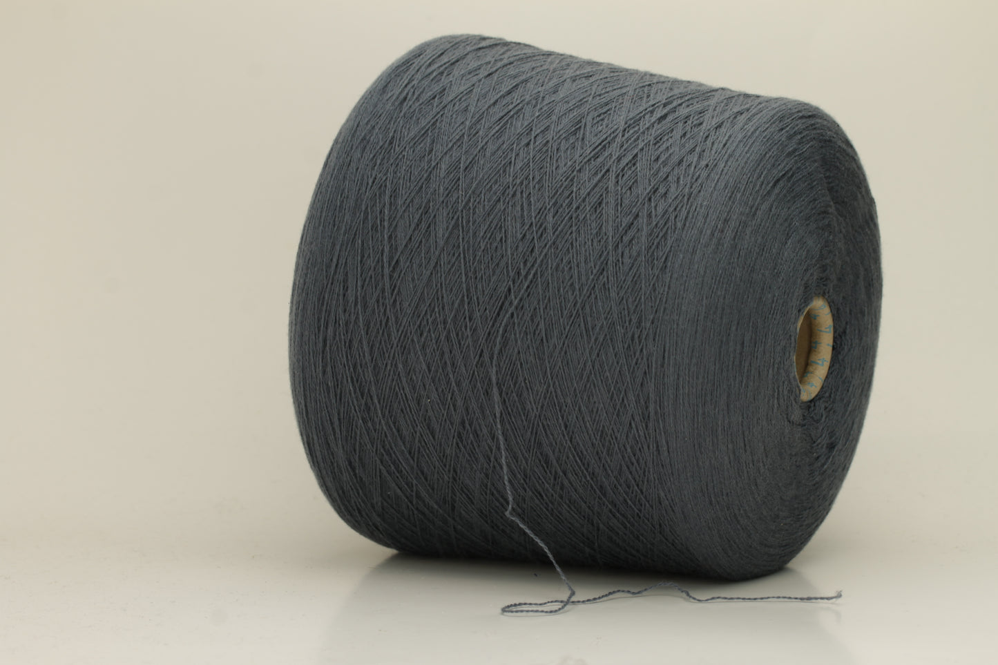 Close-up of a skein of dark, stormy blue-grey cashmere yarn with a subtle sheen. The fine, two-ply twist is visible, creating a smooth, incredibly soft thread structure that suggests luxurious warmth.