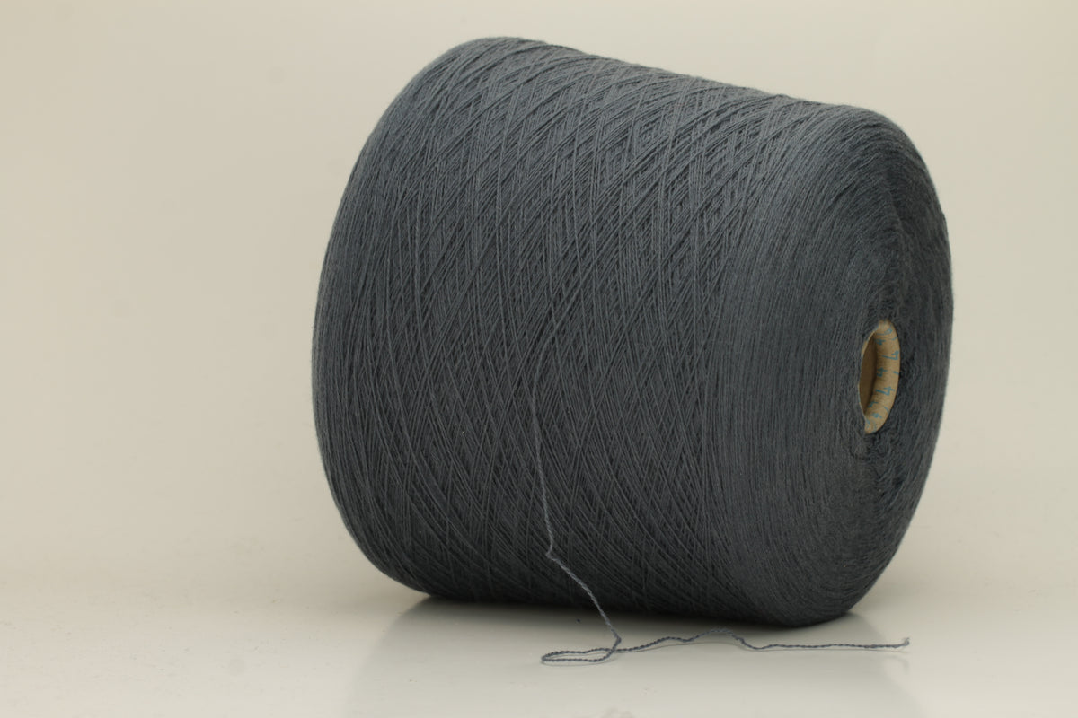 Close-up of a skein of dark, stormy blue-grey cashmere yarn with a subtle sheen. The fine, two-ply twist is visible, creating a smooth, incredibly soft thread structure that suggests luxurious warmth.