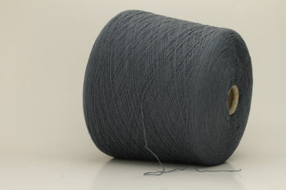 Close-up of a skein of dark, stormy blue-grey cashmere yarn with a subtle sheen. The fine, two-ply twist is visible, creating a smooth, incredibly soft thread structure that suggests luxurious warmth.