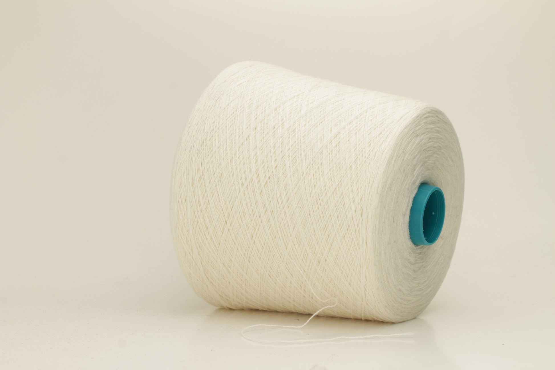 Close-up of a two-ply fine cashmere yarn, tightly twisted with a subtle matte sheen in a creamy off-white Gesso color.
