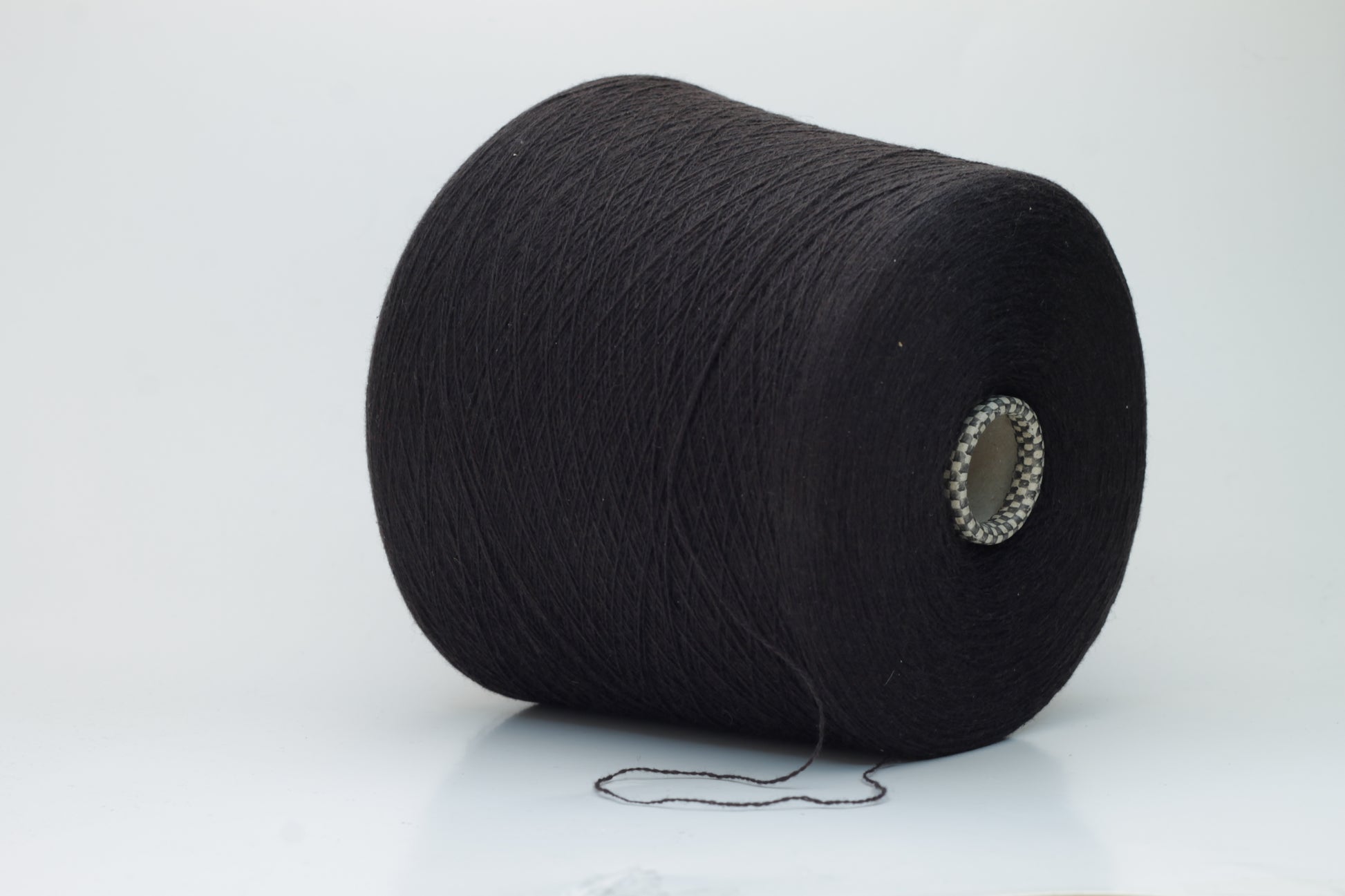 Close-up of a two-ply dark brown cashmere yarn, softly twisted with a subtle sheen, displaying its deep rich hue and delicate fuzziness, ready for luxury crafting.