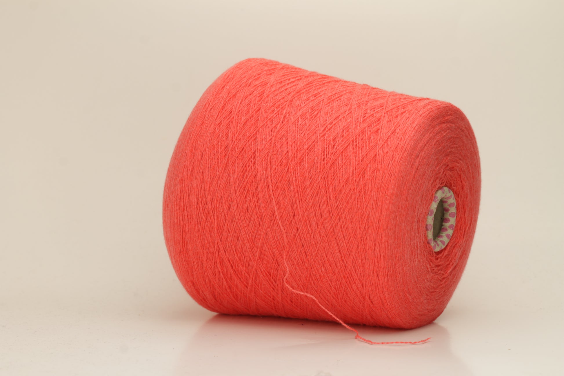 Luxurious two-ply cashmere yarn in vibrant coral (Corallo), showcasing a soft, subtle twist, smooth texture, and elegant natural sheen.