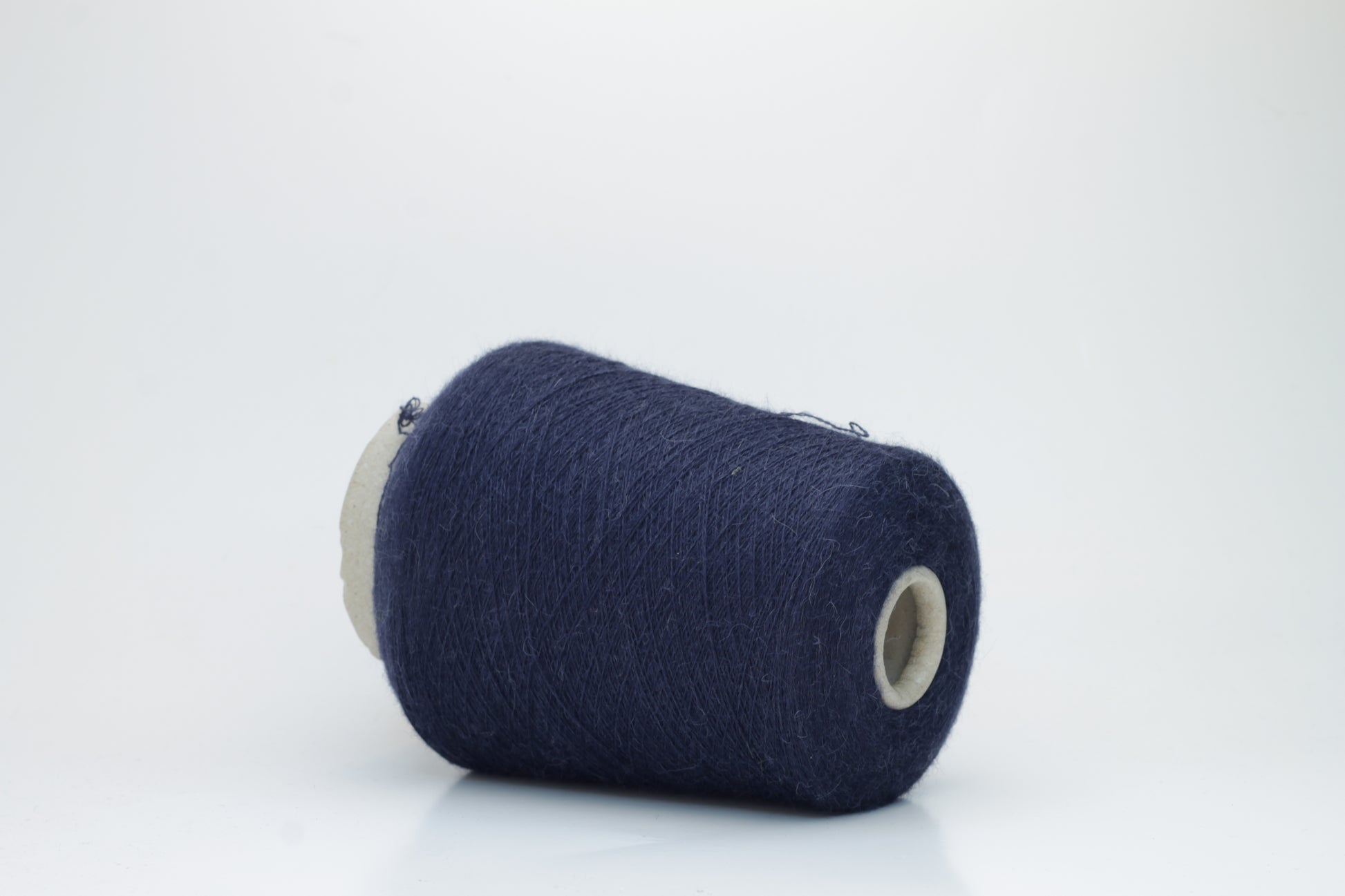 Close-up of Quipa Nm 2/28 Alpaca Merino yarn, showing its soft, slightly diffused fibers and a tight, even two-ply twist in a rich, dark navy hue.