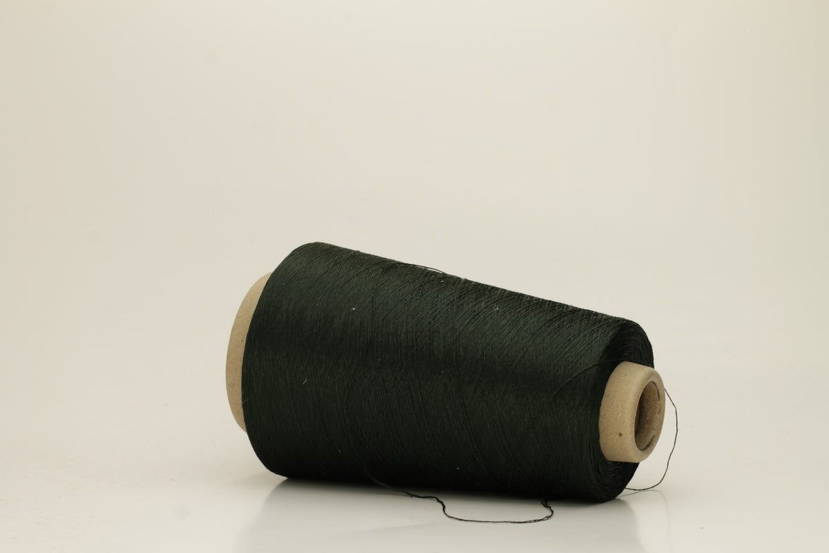 Close-up of a skein of dark green 100% silk yarn, showcasing its fine, smooth three-ply structure and elegant high sheen. The deep Autunno shade appears rich and consistent.