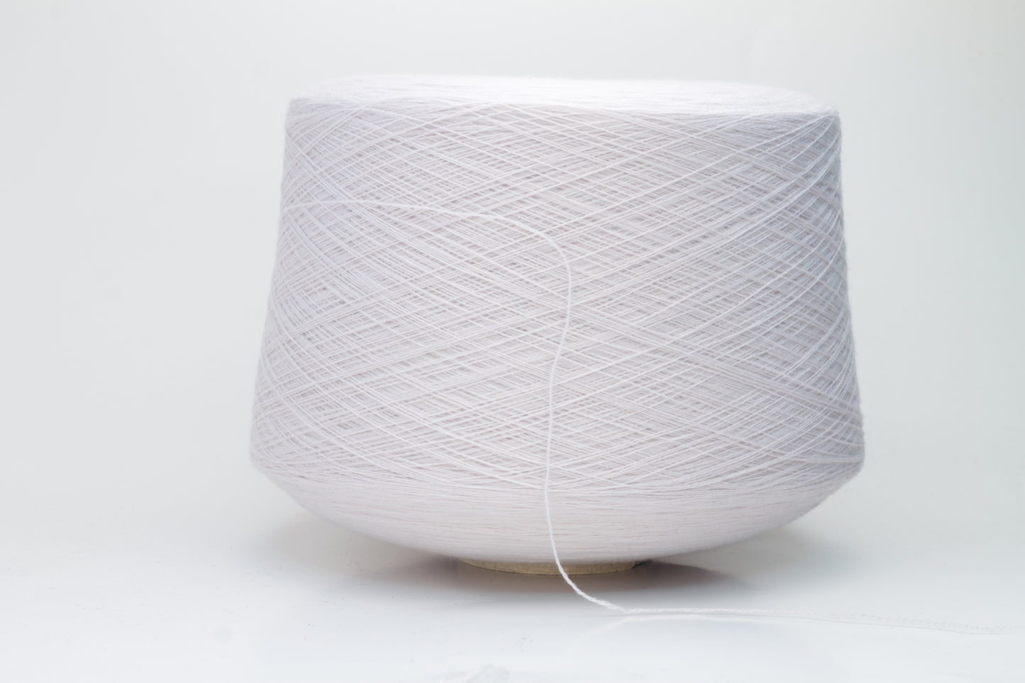 Close-up of soft, light pink Zegna Baruffa merino wool yarn with a fine ply twist, showcasing the dense thread structure and subtle sheen.