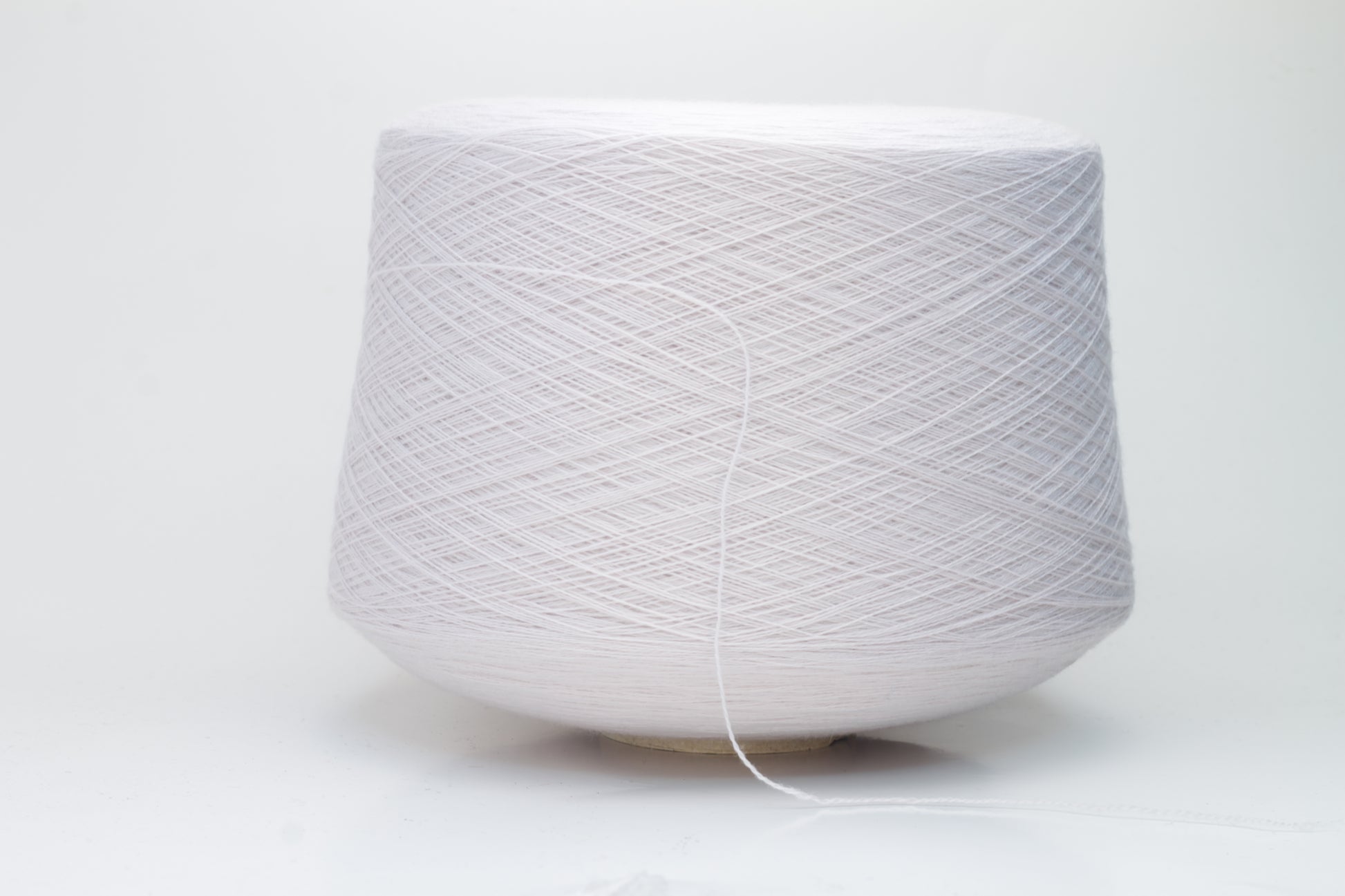 Close-up of soft, light pink Zegna Baruffa merino wool yarn with a fine ply twist, showcasing the dense thread structure and subtle sheen.
