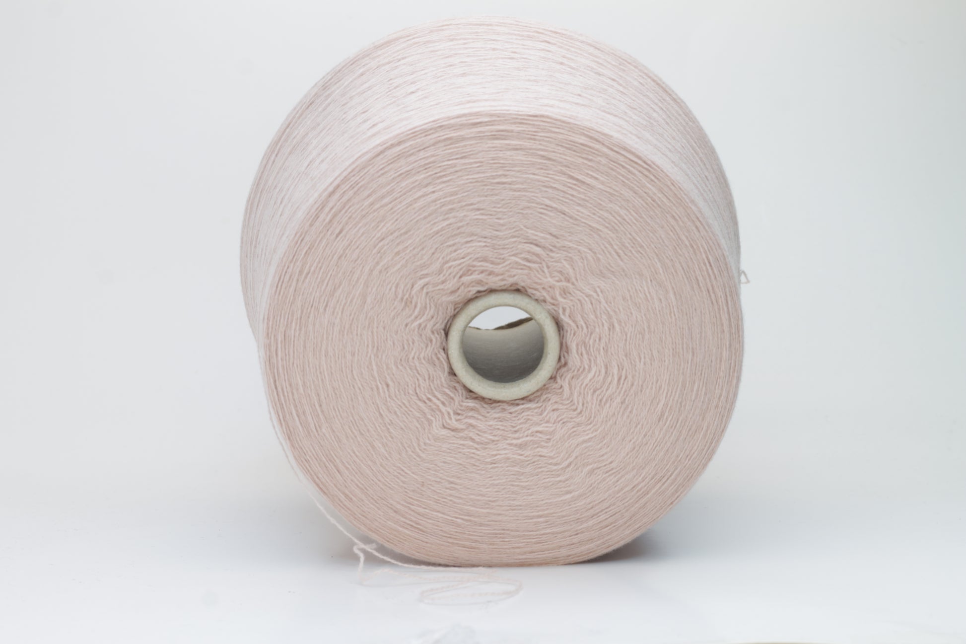 Soft, slightly fuzzy two-ply cashmere yarn in a muted, warm dusty rose color with a subtle sheen, loosely wound in a skein.