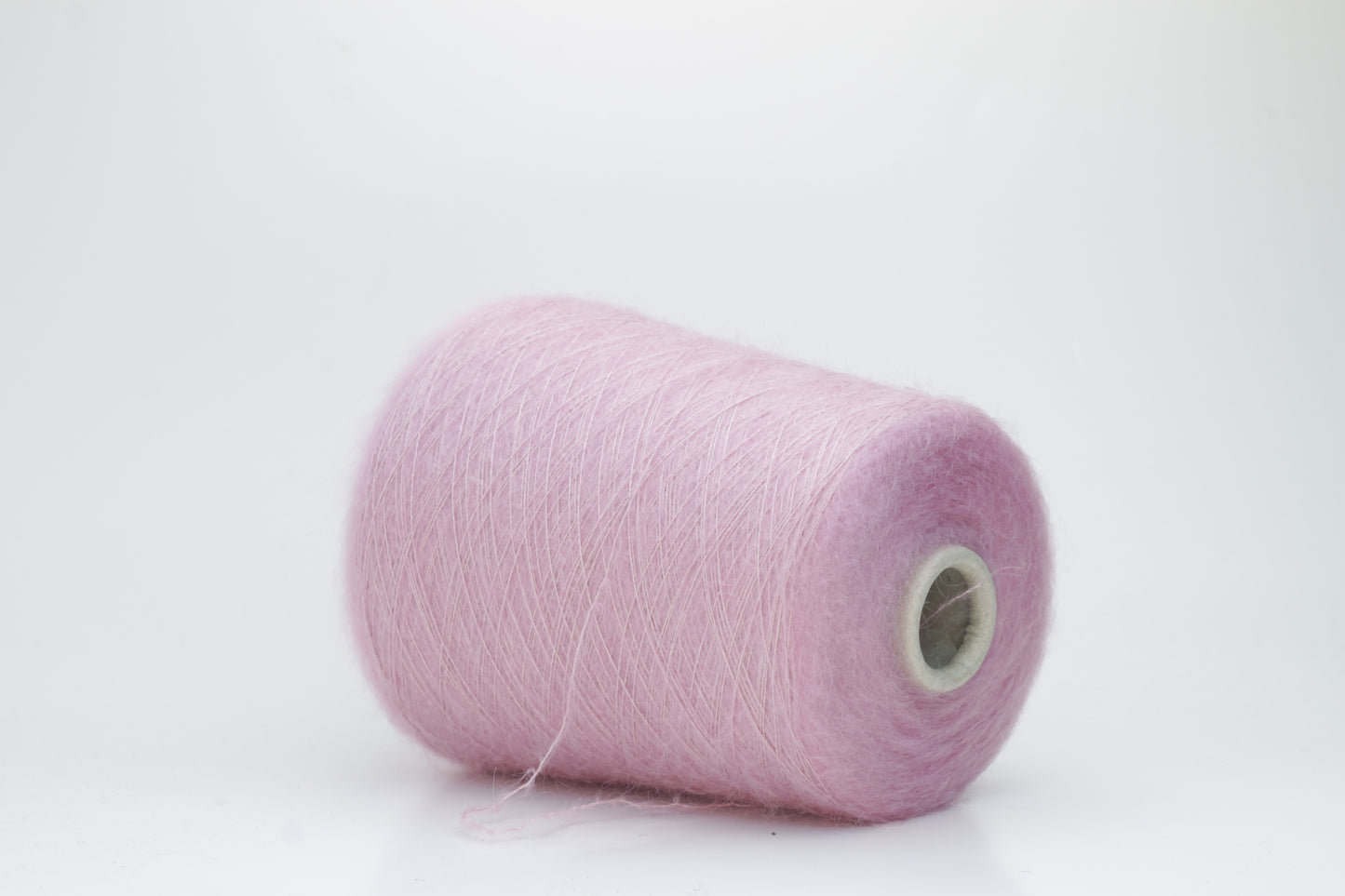 Close-up of fluffy Rosa kid mohair and silk blend yarn, subtly lustrous with a soft halo, gently twisted into a fine, delicate thread.