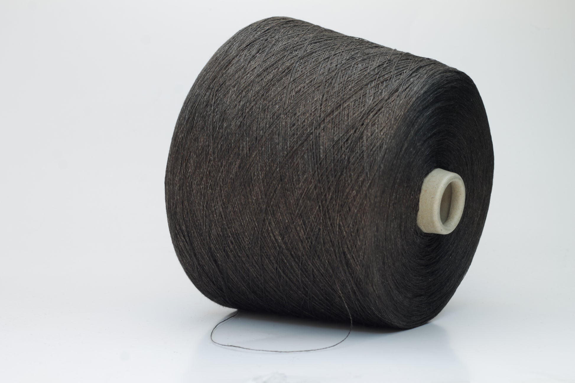 Close-up of a tightly twisted, smooth dark chocolate brown yarn strand, likely two-ply, with a subtle natural sheen.