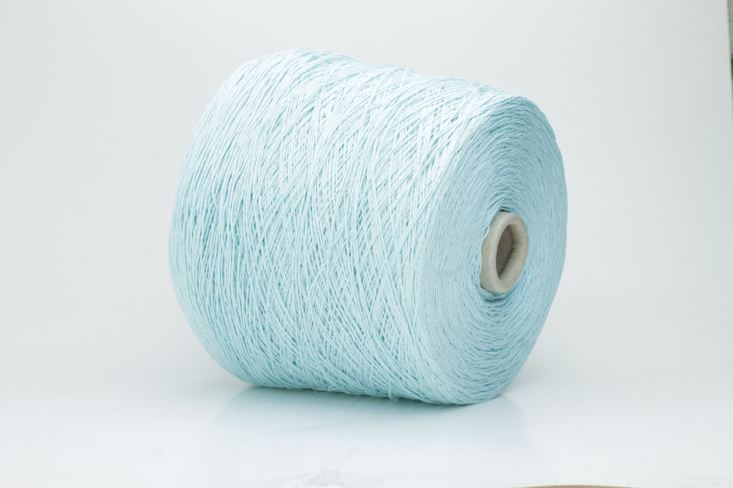 Close-up of fine, natural Linuzzo-colored 100% linen yarn, showing its smooth, slightly matte texture and subtle ply twist, coiled loosely.