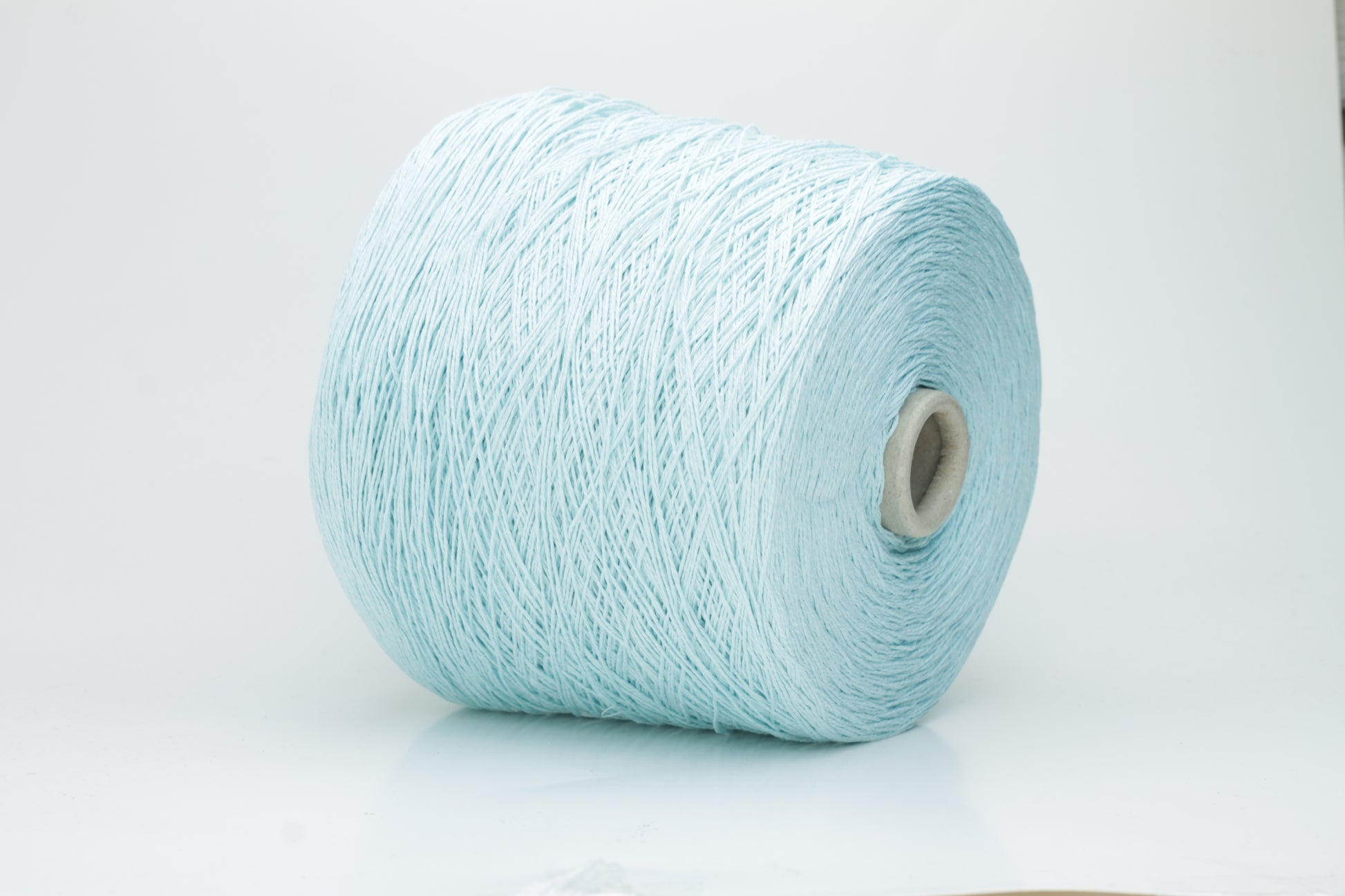 Close-up of fine, natural Linuzzo-colored 100% linen yarn, showing its smooth, slightly matte texture and subtle ply twist, coiled loosely.