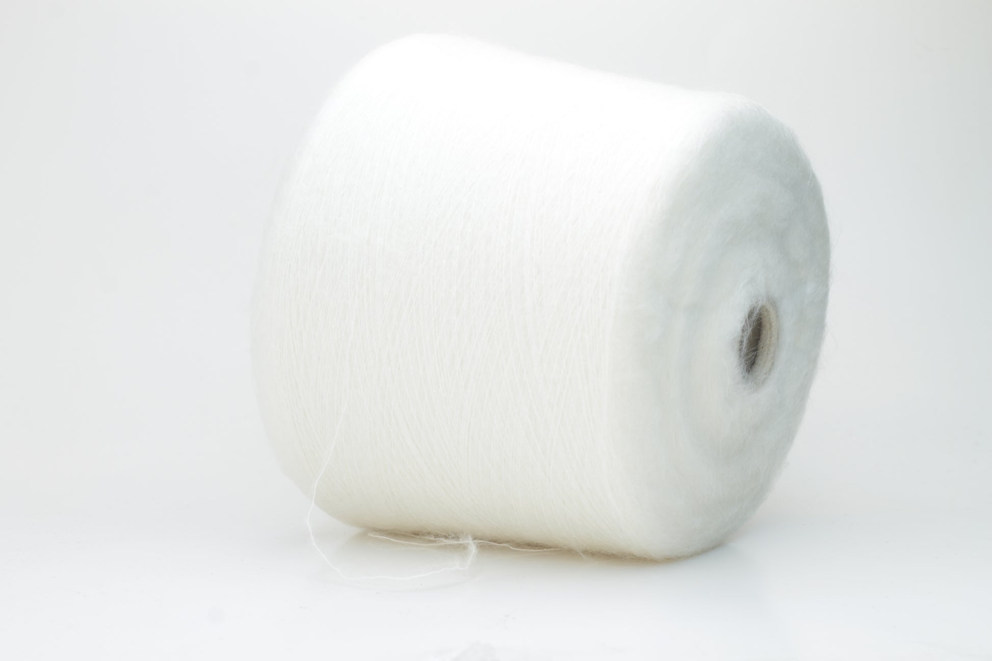 Close-up view of SuperKidMohair yarn in Aurora White color, showcasing its fluffy texture and subtle sheen. The yarn exhibits a smooth ply twist with a rich color depth.