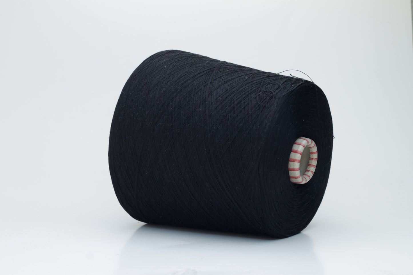 Close-up of luxurious black 100% silk yarn, tightly plied with a smooth, high-luster surface reflecting light. It has a deep, true black color, wound evenly on a cone.