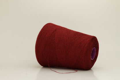 Close-up of fine 2-ply pure cashmere yarn in a rich, velvety burgundy red with subtle rosy undertones, showing its soft sheen and delicate fluff.