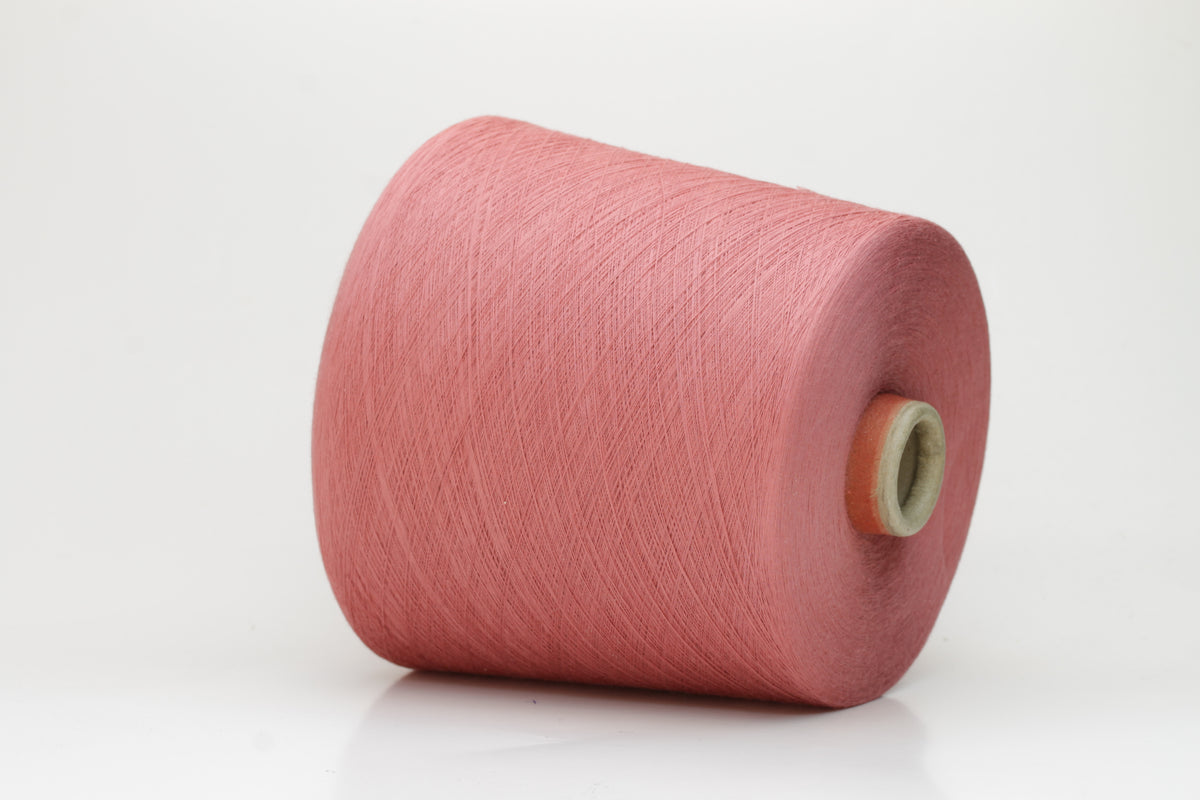 A close-up shows a finely twisted 2-ply strand of soft cotton yarn in a muted dusty rose pink, exhibiting a subtle, even texture and a delicate, gentle sheen.