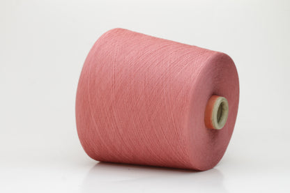 A close-up shows a finely twisted 2-ply strand of soft cotton yarn in a muted dusty rose pink, exhibiting a subtle, even texture and a delicate, gentle sheen.