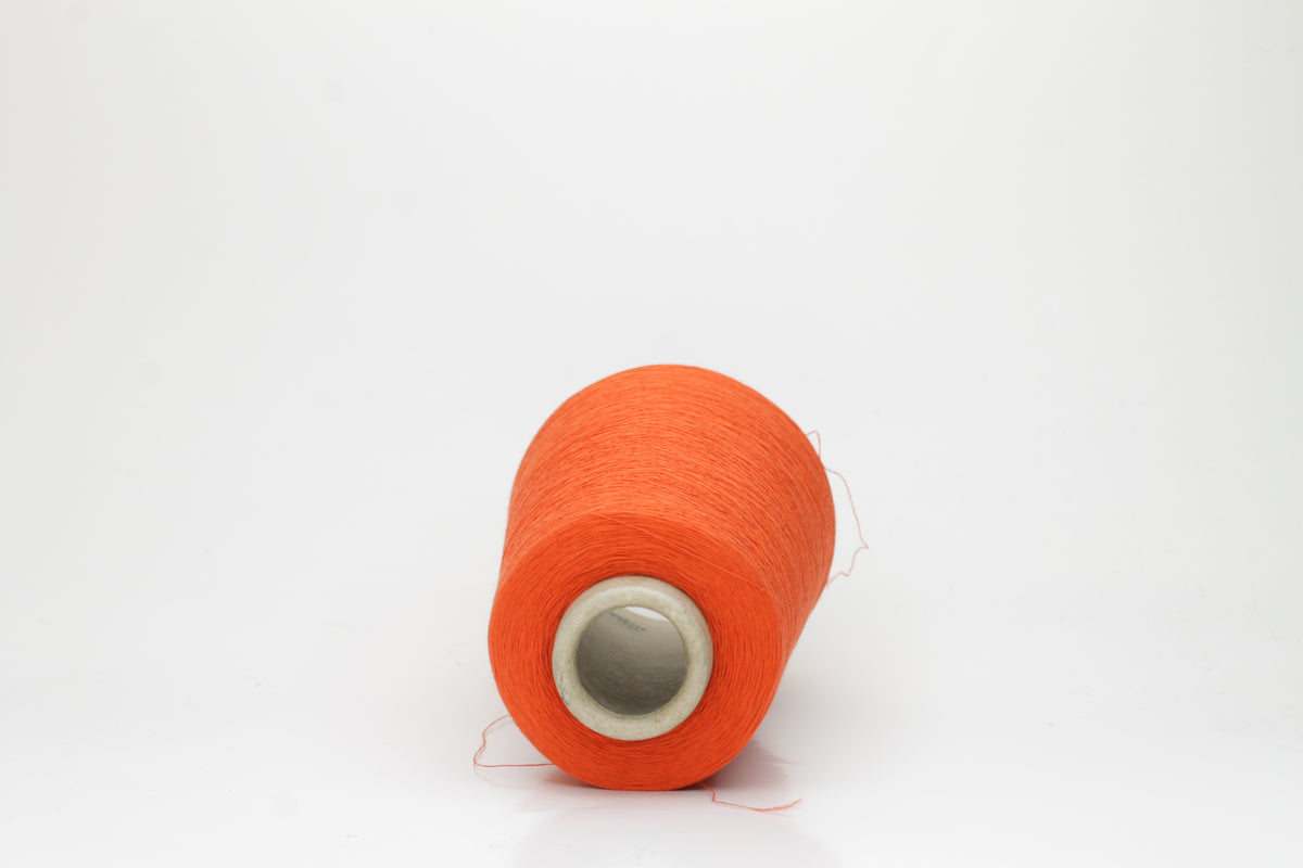 Close-up of a vibrant Mandarin Orange cotton yarn cone, revealing its smooth, tightly twisted single ply and subtle natural sheen.