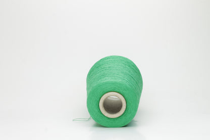 Close-up of a single strand of lustrous, single-ply 100% silk yarn in a vibrant mint green, showcasing its smooth texture and elegant sheen.