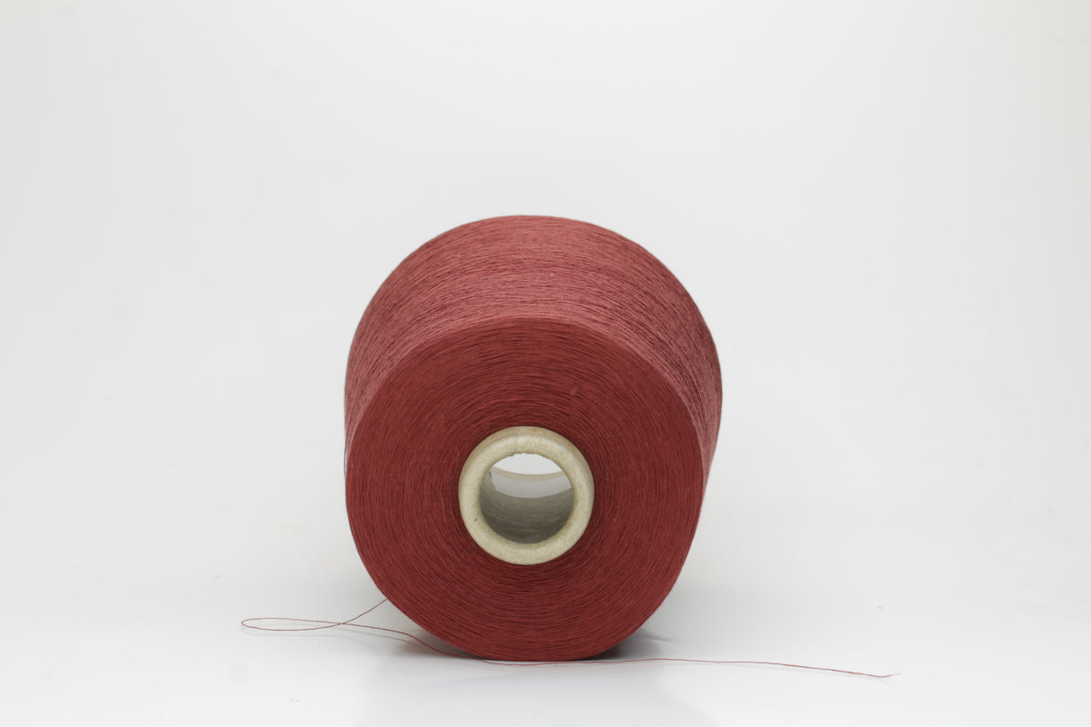 Close-up of a tightly twisted, matte finish cotton yarn in a rich, earthy warm terracotta hue, showcasing its smooth texture and consistent ply structure, ready for crafting.