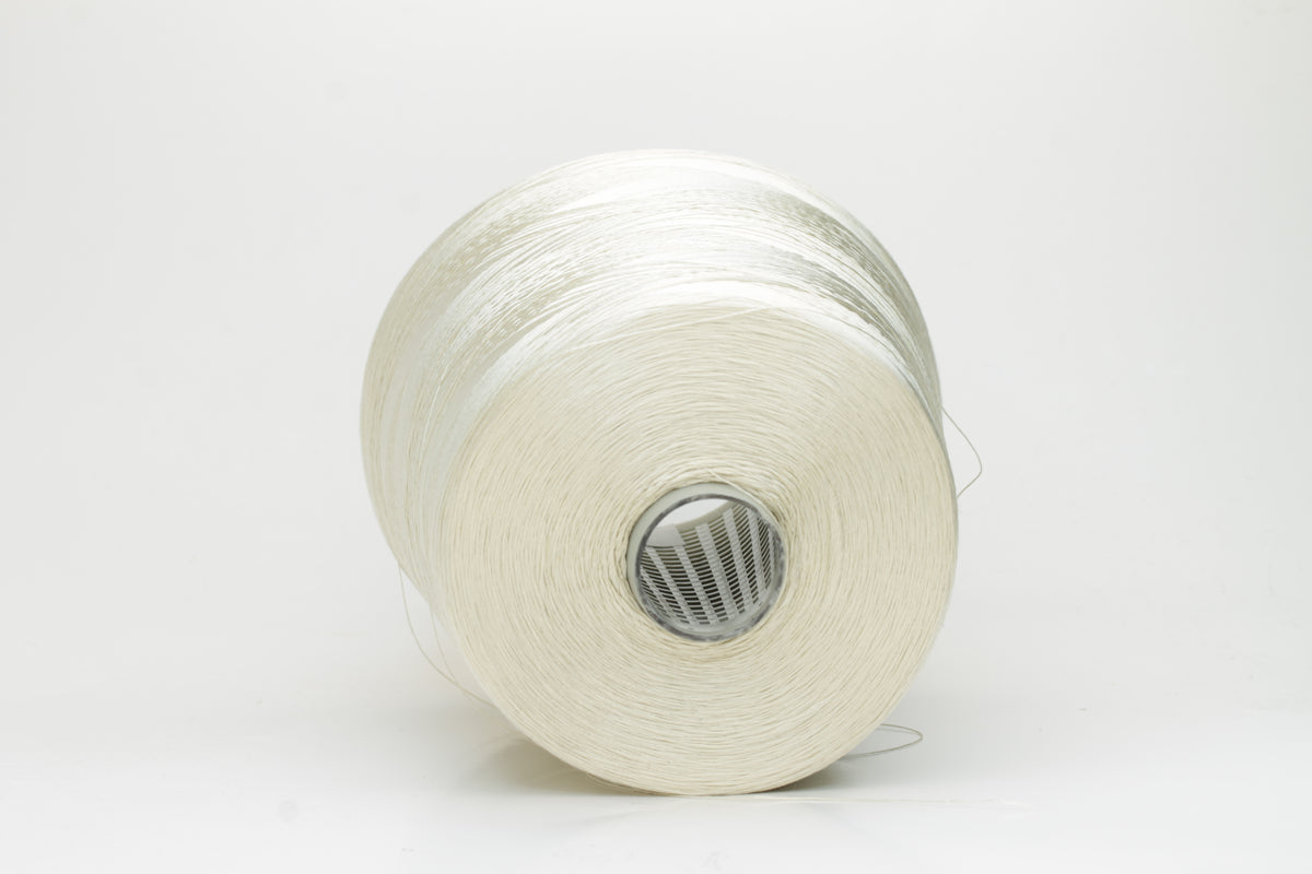 Close-up of finely plied natural silk yarn in a pale, warm champagne tone, reflecting light with a soft, radiant shimmer.