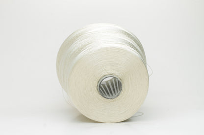 Close-up of finely plied natural silk yarn in a pale, warm champagne tone, reflecting light with a soft, radiant shimmer.