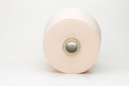 Close-up of finely spun, delicate powder pink cotton yarn, showcasing its soft, matte finish and subtle, even twist with excellent stitch definition.