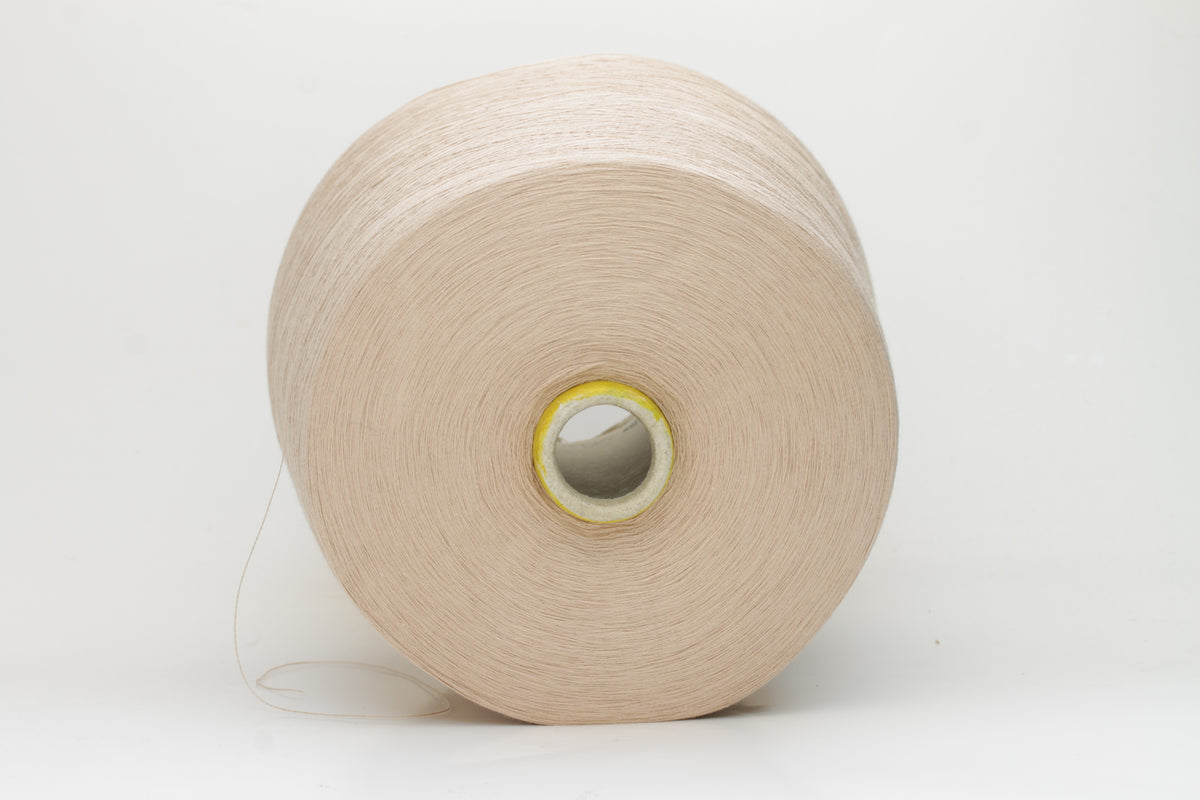 Close-up of a vibrant, Powder Pink Beige cotton yarn. The smooth, tightly twisted 2-ply thread exhibits a subtle sheen and deep, saturated color.
