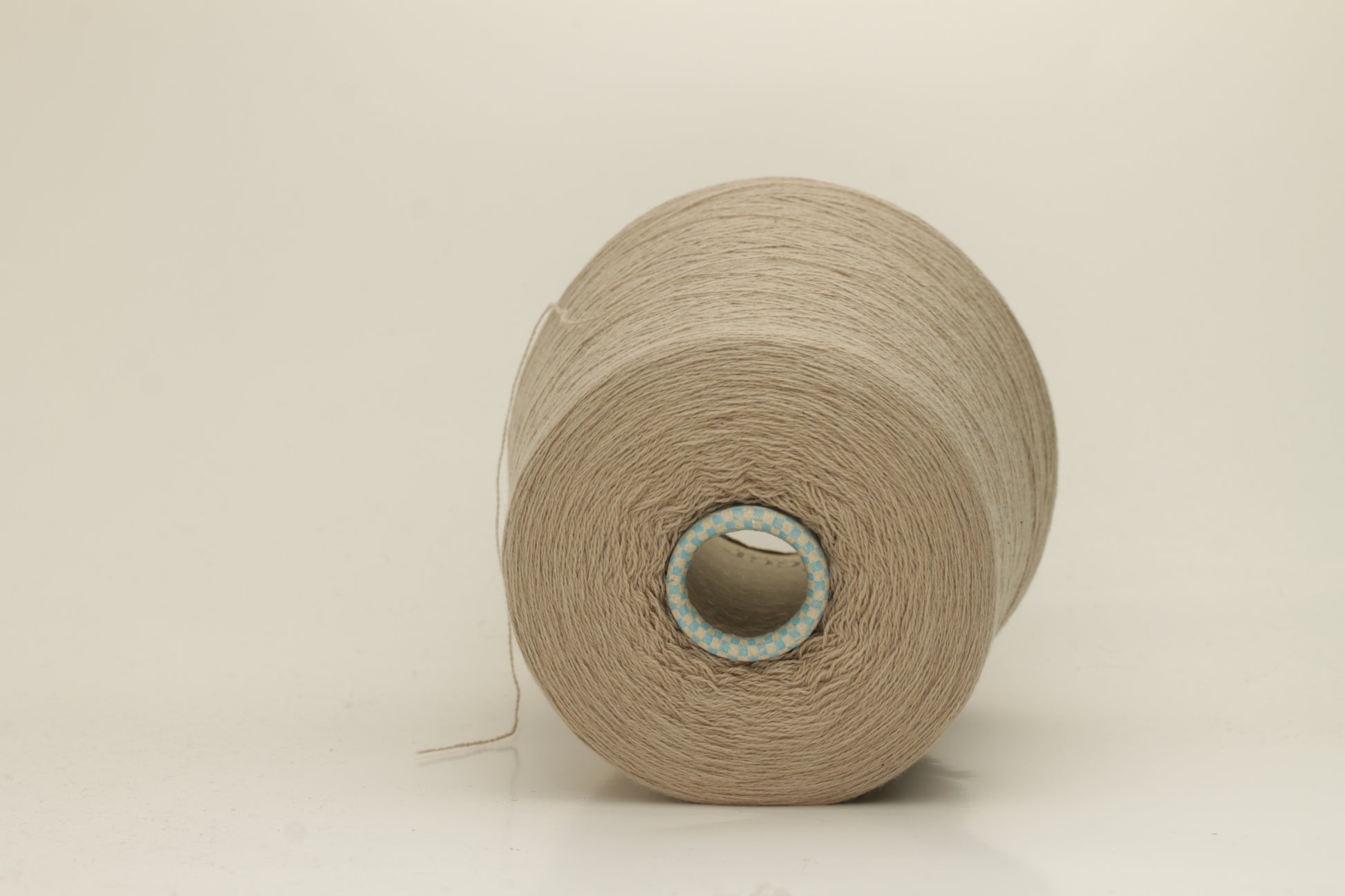 Close-up of a skein of incredibly soft, two-ply cashmere yarn in a deep, warm Mastice beige. Fine fibers with a subtle halo and elegant twist visible.