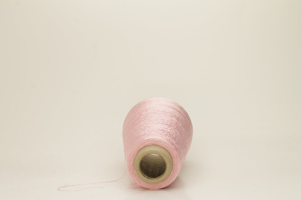 Close-up of pristine Rosa, finely plied 100% silk yarn, twisted smoothly to reveal a high, lustrous sheen and uniform structure.