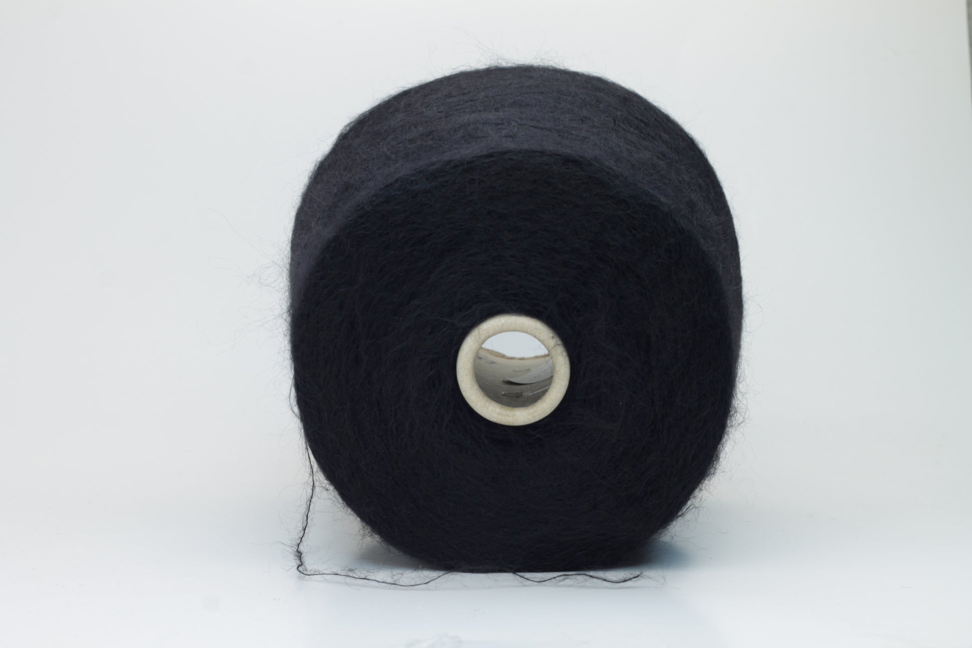 Close-up shot of the Black SuperKidMohair yarn, showcasing its dense ply twist and subtle sheen. The fibers appear fluffy and richly colored, creating a luxurious tactile impression.