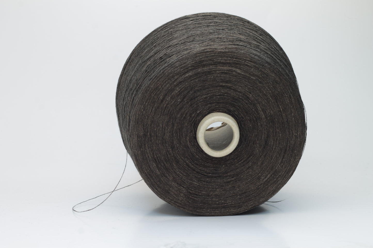 Close-up of a tightly twisted, smooth dark chocolate brown yarn strand, likely two-ply, with a subtle natural sheen.