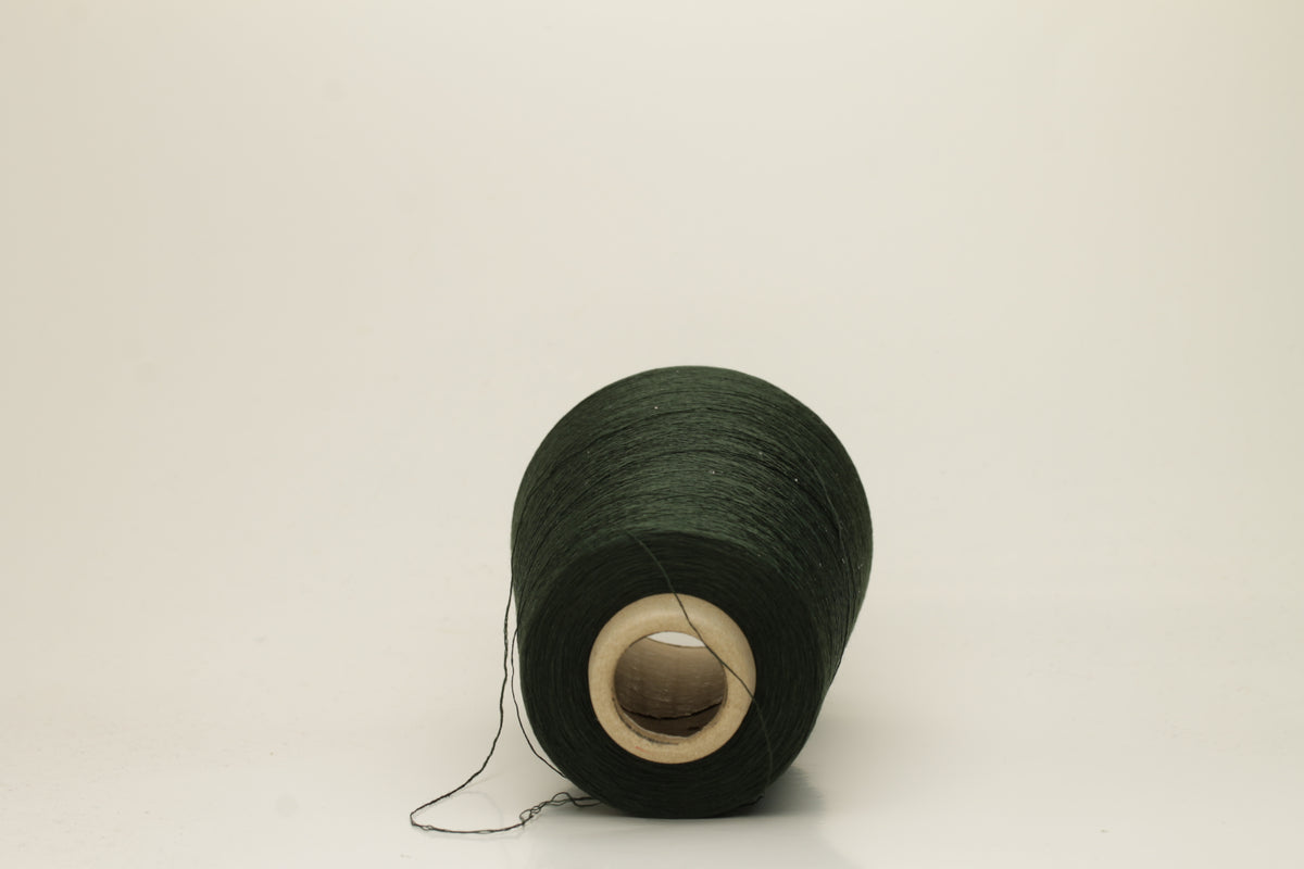 Close-up of a skein of dark green 100% silk yarn, showcasing its fine, smooth three-ply structure and elegant high sheen. The deep Autunno shade appears rich and consistent.