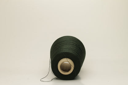 Close-up of a skein of dark green 100% silk yarn, showcasing its fine, smooth three-ply structure and elegant high sheen. The deep Autunno shade appears rich and consistent.