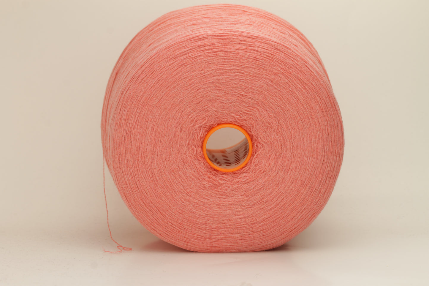 Close-up of soft, two-ply cashmere yarn in a delicate, even pink shade, showcasing its fine, slightly fuzzy texture and subtle sheen.